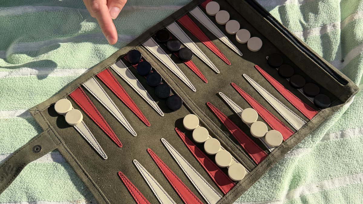 Playing backgammon on a Suede and Stone travel set at the beach