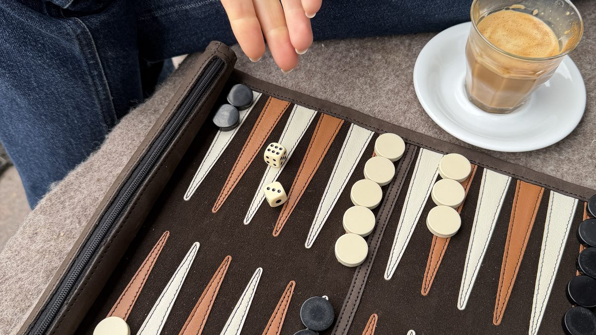 Hands playing backgammon on a Suede and Stone set